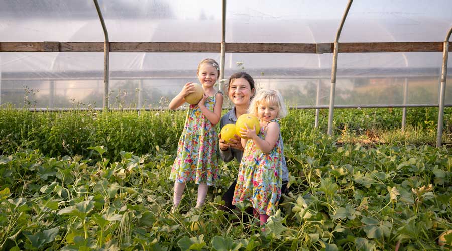 Melissa and her daughters Ky and Ada showing off melons grown in the greenhouse